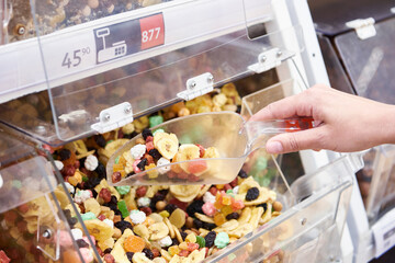 Hand with scoop takes mixture of nuts and dried fruits