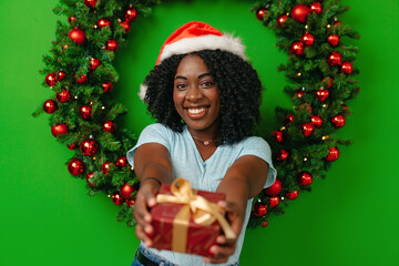 African woman smiling standing against Christmas wreath decor at home