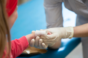 The hands of the doctor bandage the sore finger with a bandage of the child. Injury and wound on...