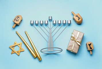 Menorah with dreidels, candles, David star and gift for Hannukah celebration on blue background