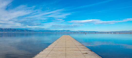 Wooden pier,  beautiful blue lake and clouds reflection ( Delta del Ebro,  Spain)