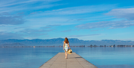 Woman walking on wooden pier ( Catalonia, Delta del Ebro, Spain)