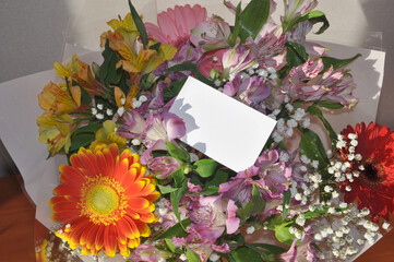 A business card in a bright multi-colored bouquet of flowers. Mockup