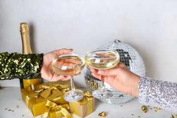 Women with glasses of champagne, disco ball and Christmas gifts on white background, closeup