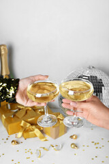 Women with glasses of champagne, disco ball and Christmas gifts on white background, closeup