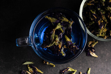 Butterfly pea flower tea in a clear glass on a black background.