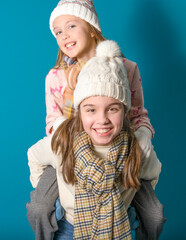 Two sisters or teenage friends play leapfrog. Winter motif and clothes. studio photo. Sweaters,...
