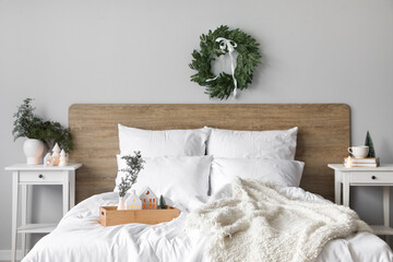 Interior of light bedroom with Christmas wreath and candle holders