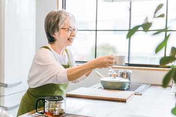 家・カフェのキッチンでコーヒーを淹れるアジア人高齢者女性
