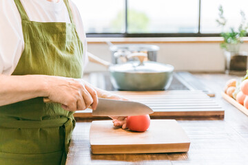 家のキッチンで料理を作るアジア人の高齢者女性
