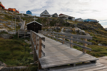 Casas de madera de colores en pueblo costero con icebergs flotando de fondo.
