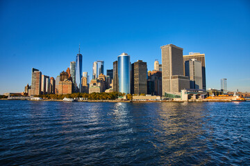 Fototapeta na wymiar Beautiful New York City skyline from the water with sunlight hitting southern Manhattan