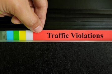 Hand picking traffic violations file record in black binder folder. Civil offenses concept.