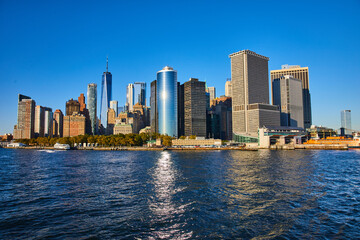 Obraz premium Stunning New York City skyline from boat with sun shining over skyscrapers