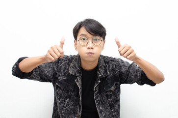 handsome attractive Asian man wearing jeans jacket smiling happily and giving thumbs up as...