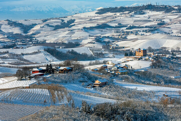 Hills and vineyards covered with white snow in Piedmont, Italy.