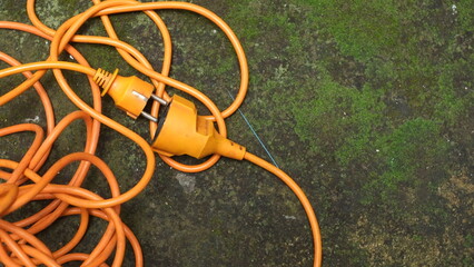 Orange cord with plug on mossy floor