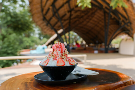 Japanese shaved ice dessert , Strawberry kakigori bingsu topped with sweet ice cream almond stick strawberry sauce and condensed milk in cafe. Traditional summer dessert menu in Japan.