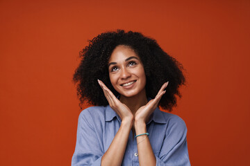 Smiling african american woman posing isolated over red wall