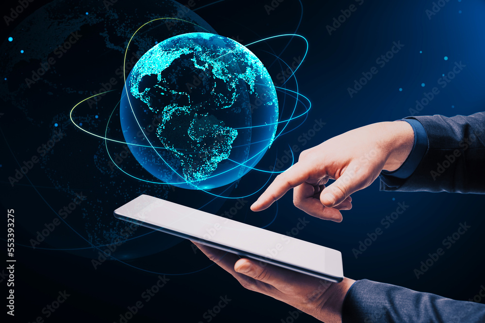 Poster close up of businessman hand pointing at cellphone with creative glowing globe hologram on dark back