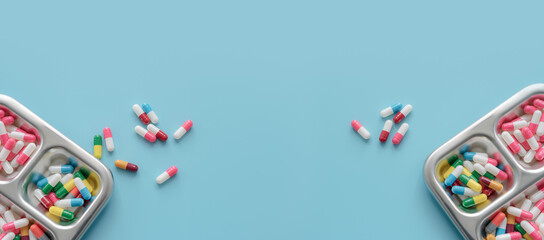 Above view of Colorful antibiotic capsule pills on tray and blue background. Antibiotic drug...