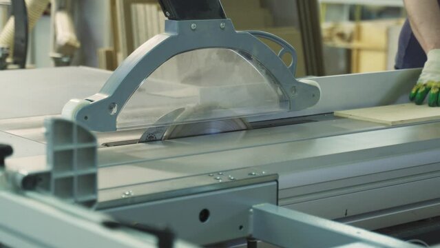 A circular saw cuts through a hardboard wood panel. Woodworking. Furniture manufacturing.