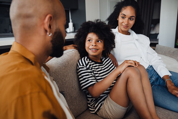 African american family sitting on sofa at home - Powered by Adobe