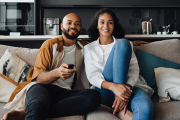 African american couple watching TV while sitting on sofa