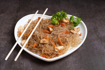 Glass bean funchose vermicelli on a plate with chopsticks on a dark background