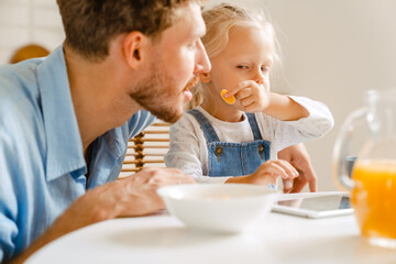 Young white father and his little daughter having breakfast at home