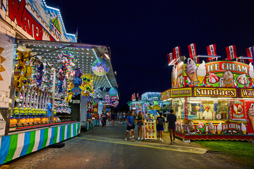 Nighttime at carnival county fair with vendors of games and food
