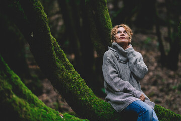 Serene woman sitting and relaxing on a green musk covered trunk in forest woods. Happy...