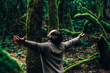 Back view of man enjoying and feeling the forest woods around him. People and nature care love. Environment, Stop deforestation, travel tourist in the green musk woods. Scenic place destination