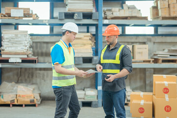 Warehouse workers in helmets checking goods and supplies on shelves with goods background in warehouse worker packing in a large warehouse in a large warehouse. Logistics industry concept..