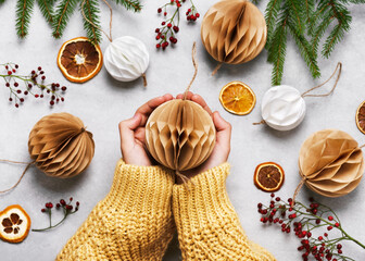 Handmade Christmas Honeycomb ball made from white und brown coffee filter in girl hands....