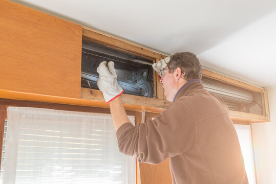 Broken house roller shutter. Man agape and surprised by the damage who requires the call of a specialized repairer. Concept of repairing or replacing a roller shutter with a more modern one