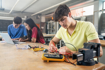 College Student working on electronics circuit in the science technology workshop - Digital...