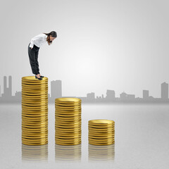 Asian businesswoman standing and looking down the coin stack