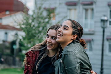 couple of positive funny women hugging in the park