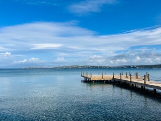 Fototapeta na wymiar Empty wooden pier at the blue sea, beautiful sea horizon, transparent water
