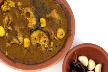 Fish curry served in traditional mud pot with fish curry ingredient. Fresh fish curry with chilli, pepper and garlic. Special south Indian fish curry. Tamilnadu and Kerala style fish curry