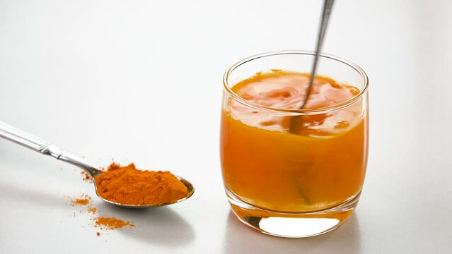 Mixing turmeric powder in a glass of water.