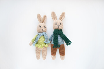 A pair of knitted bunny toys - girl in a dress, boy in pants.