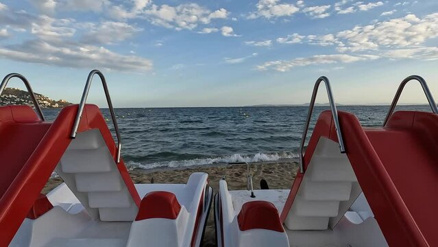 Two pedal boats on the beach. Red and white pedal boats with slides parked on a sand beach. Touristic travel destination in Spain. Costa brava beach town scene. Children attraction. 