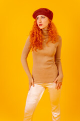 Portrait of red-haired woman in a red beret on a yellow background, studio shot, vertical photo