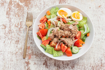 Healthy food tuna salad add egg in white bowl on wood background.