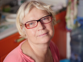 Portrait of a aged woman at the kitchen. Selective focus with shallow depth of field.