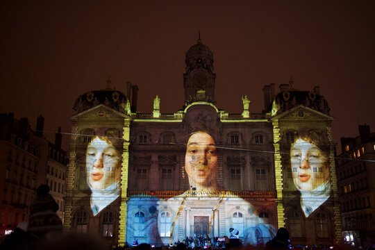 Magnificent Lyon city hall on the Terreaux square during the famous festival of lights of Lyon, France. The image of a classic old painting representing 3 characters is projected.