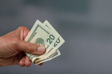close-up of a man's hand holding a bunch of twenty dollar bills / greenbacks
