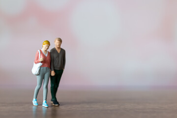 Miniature people man and woman in casual cloth standing together on pink background